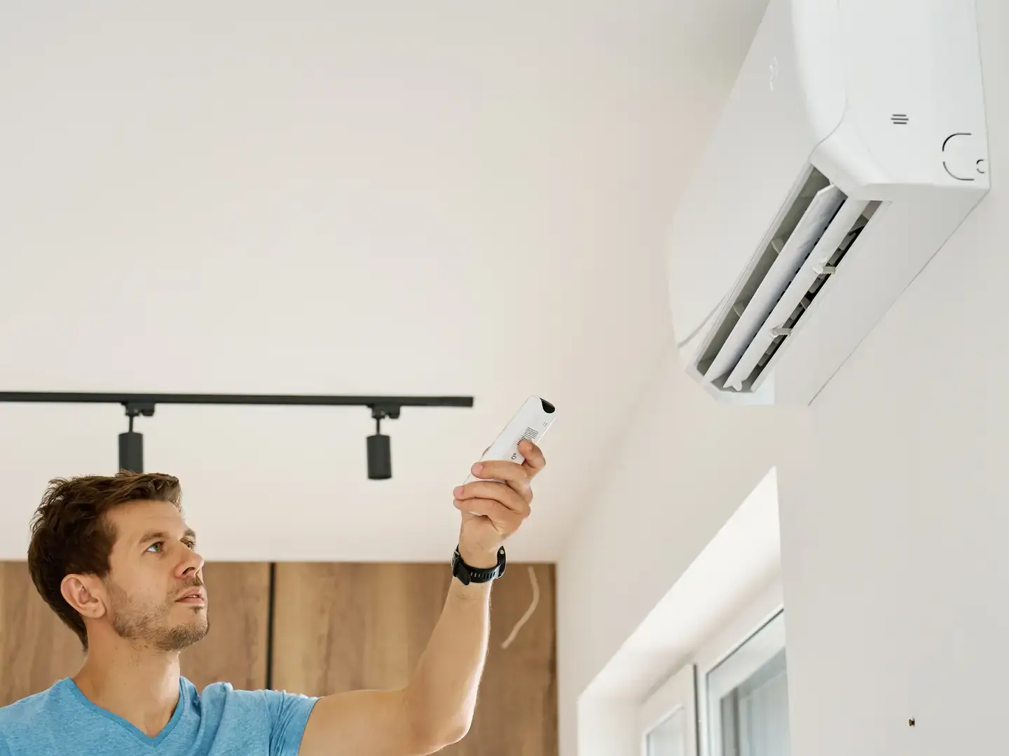 Personne mettant en marche une climatisation murale pour vérifier le mode de soufflage