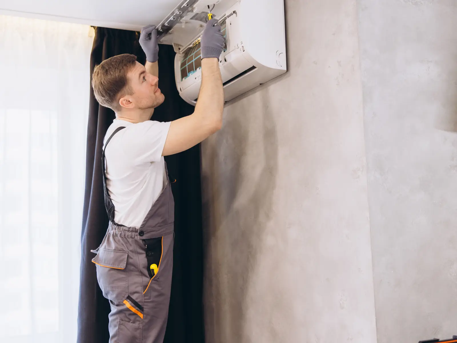 Technicien réparant un split mural installé en hauteur qui ne produisait plus de froid