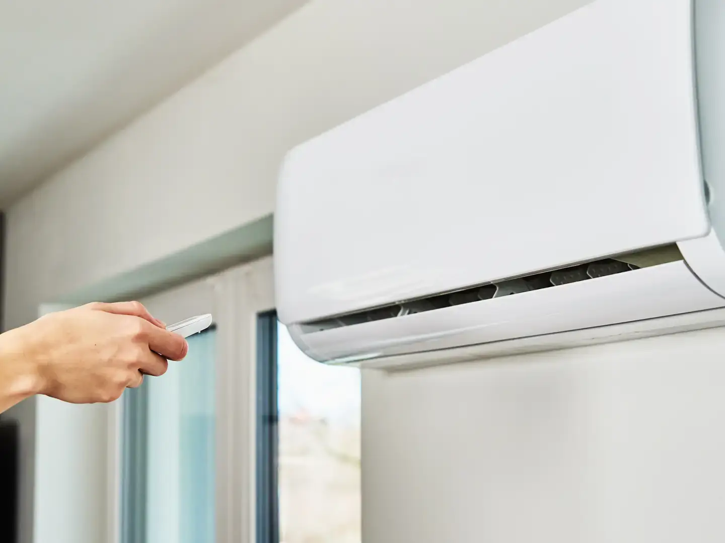 Utilisateur réglant la température d'une climatisation avec la télécommande